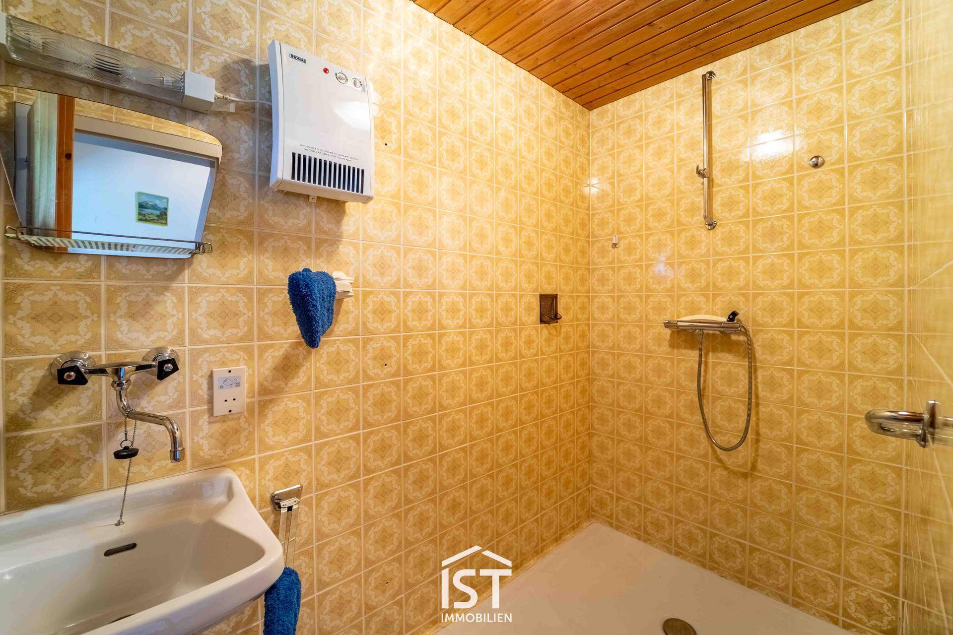 Kleines Badezimmer mit gelben Fliesen, Dusche und Waschbecken.