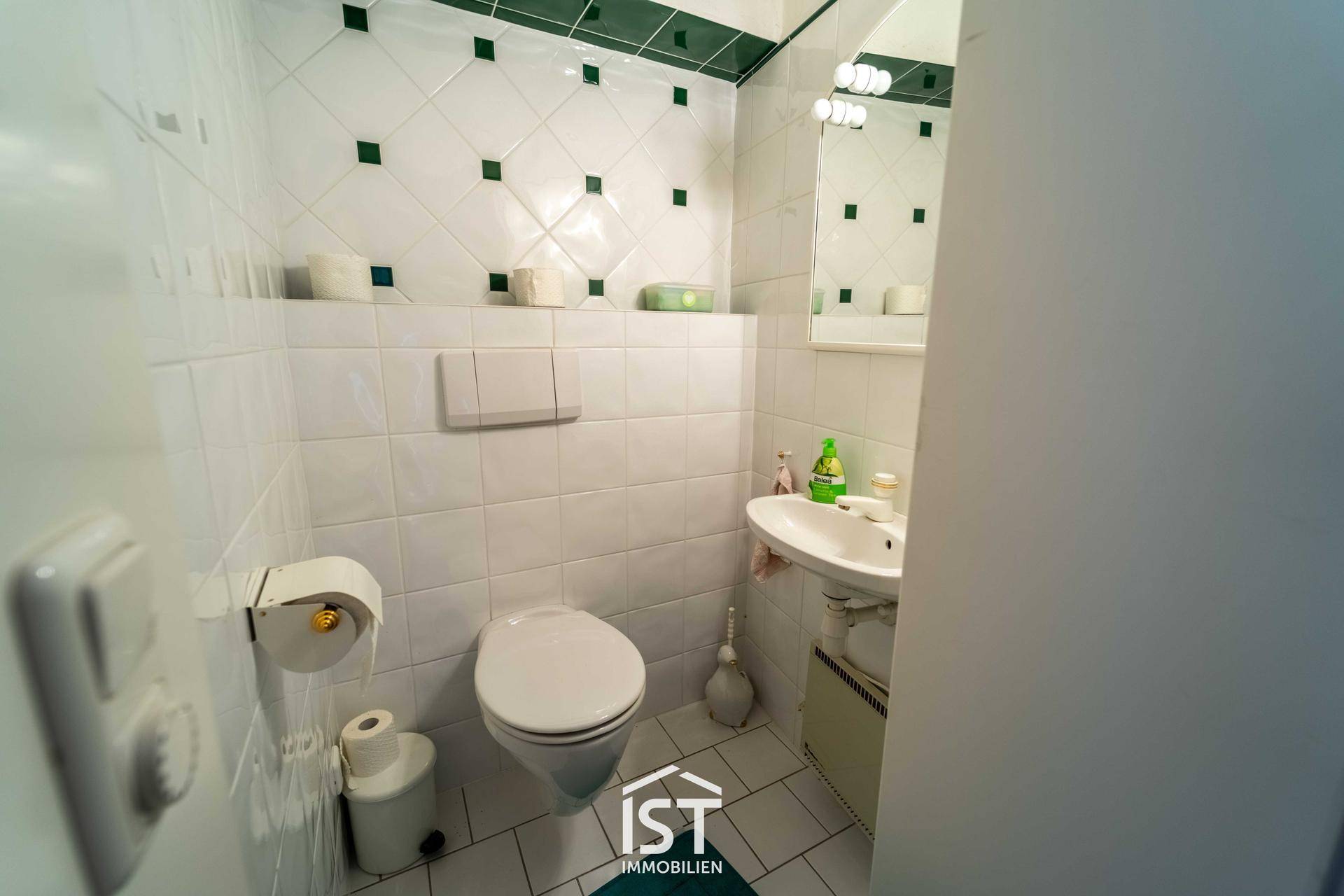 Kleines Gäste-WC mit weißen Fliesen, Wand-WC und Waschbecken.