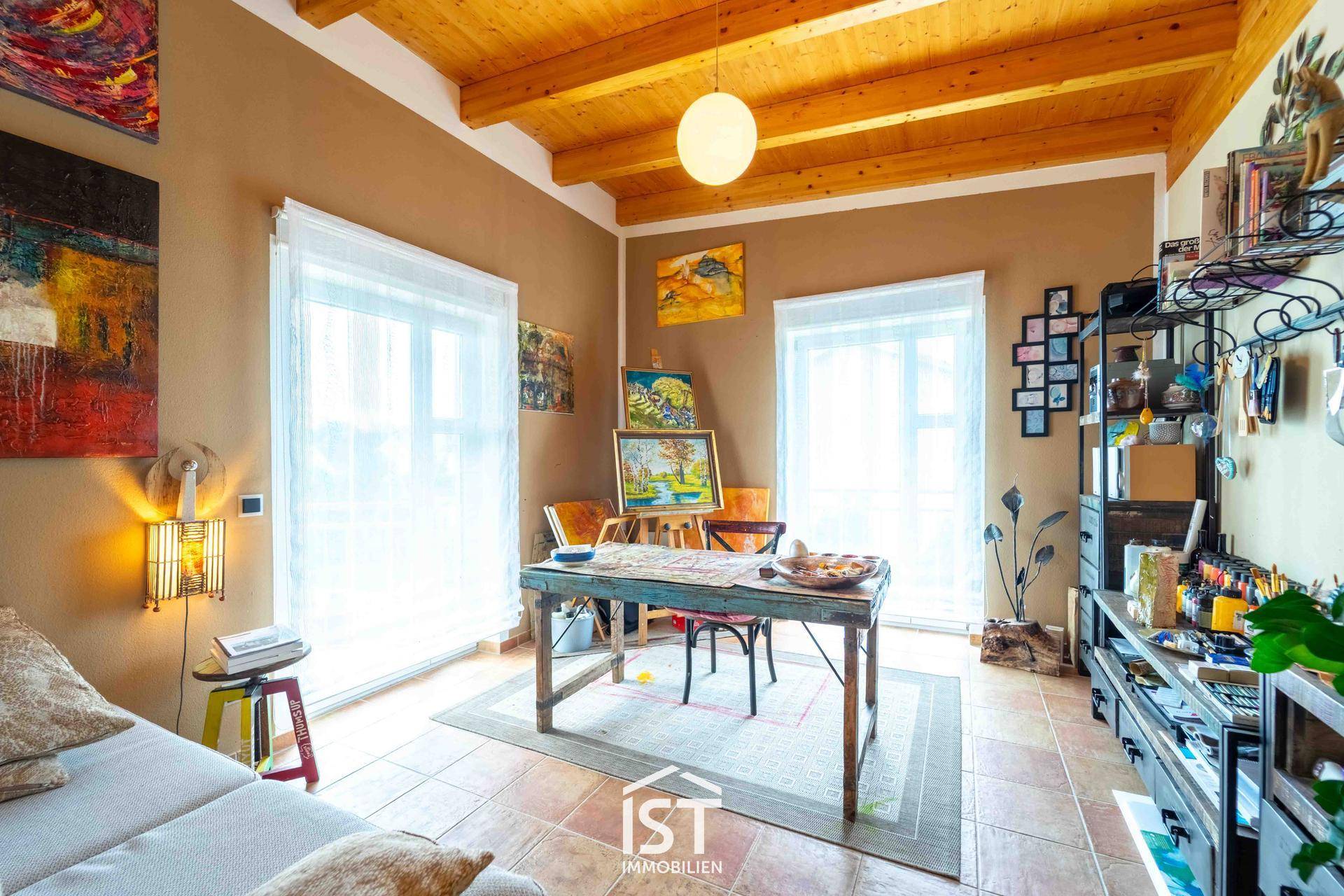 Helles Arbeitszimmer mit Holzbalkendecke, Terrakotta-Boden und zwei großen Fenstern.