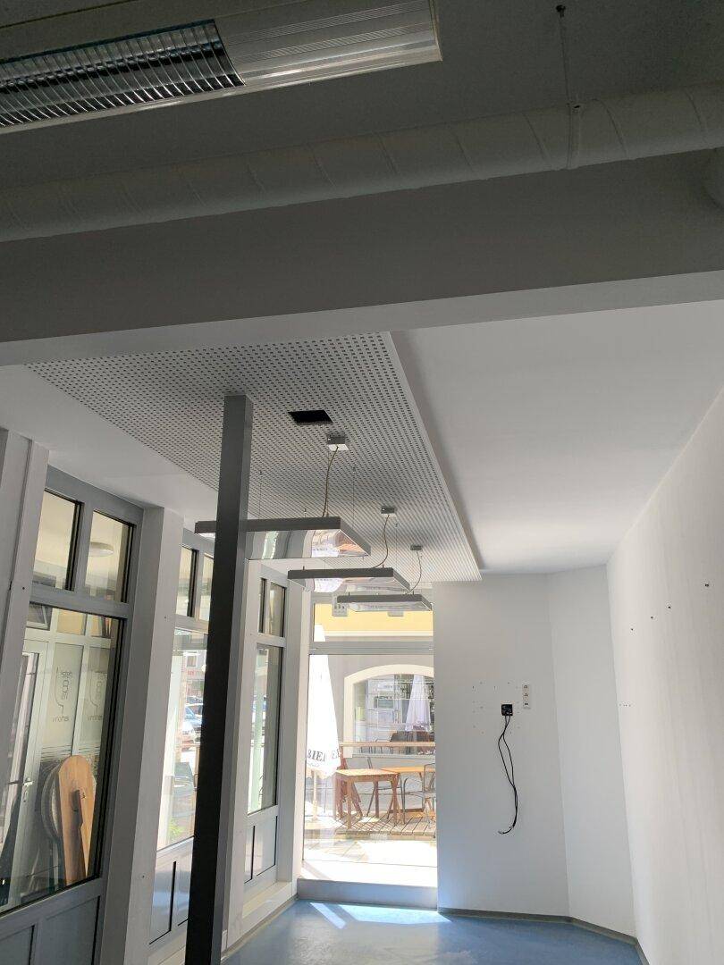 Heller Gewerberaum mit großen Fenstern zum Eingangsbereich und moderner Deckenbeleuchtung.
