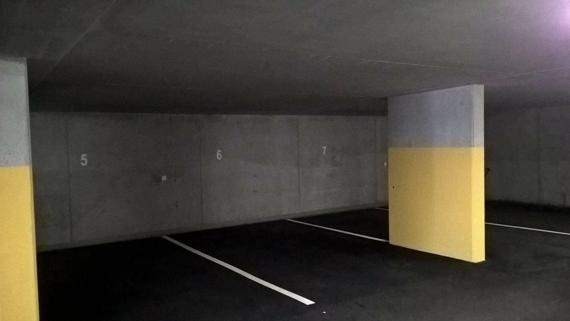 Geräumige Tiefgarage mit nummerierten Stellplätzen und gelb gestrichenen Säulen zur Orientierung.