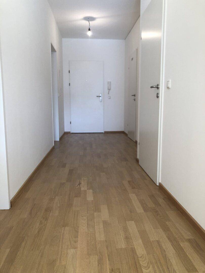 Langer, heller Flur mit Parkettboden und mehreren Türen zu den angrenzenden Räumen.