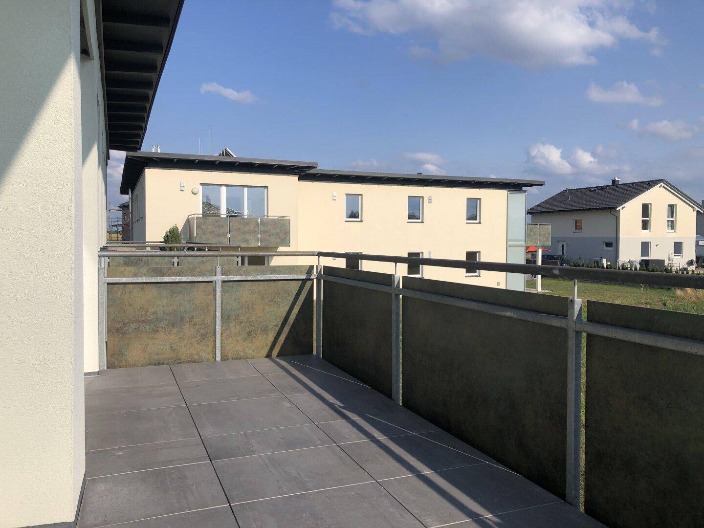 Geräumiger Balkon mit Fliesenboden und Blick auf die umliegenden Gebäude.