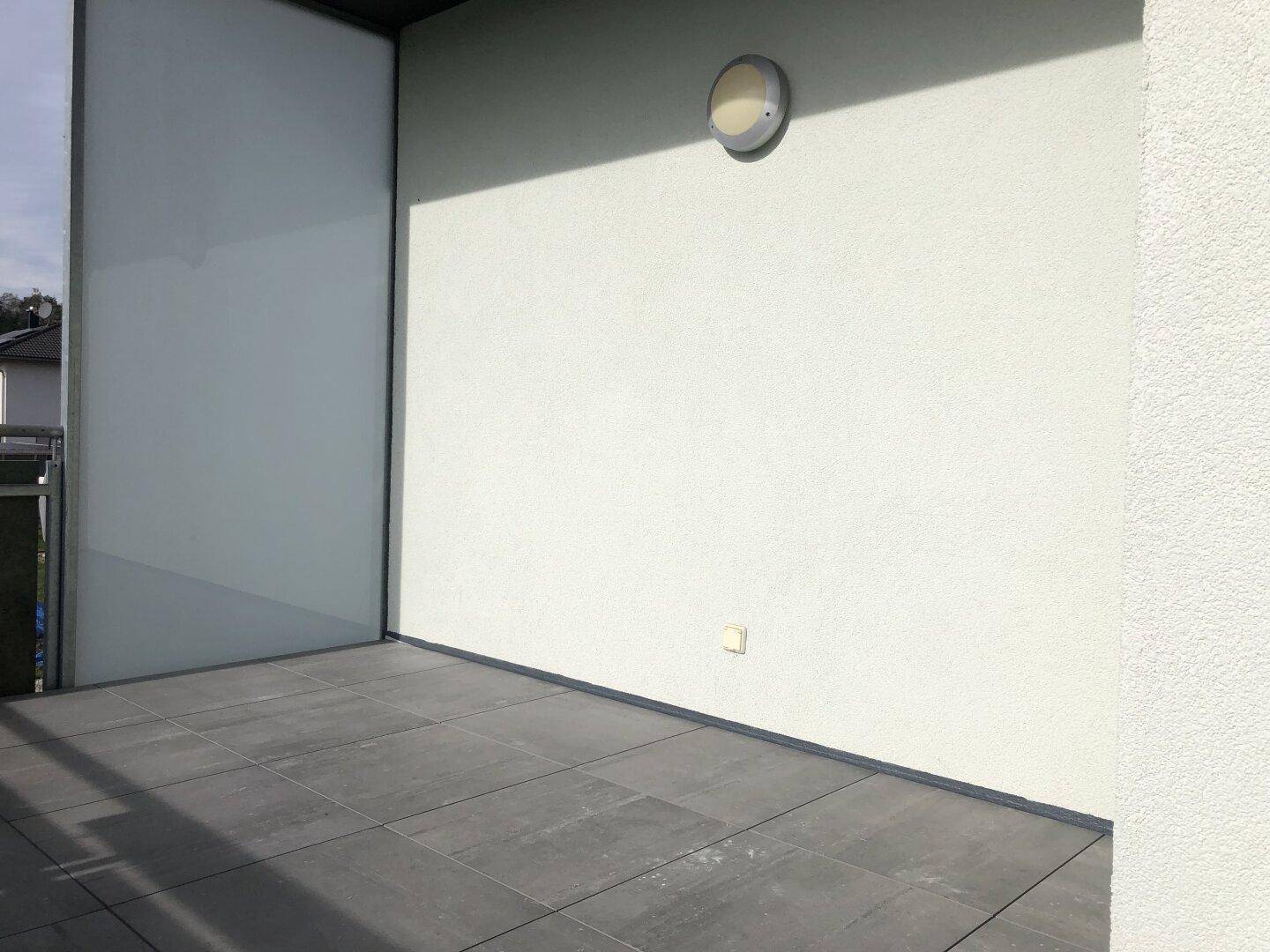 Balkon mit modernem Fliesenboden und schützender Brüstung, ideal für Entspannung.