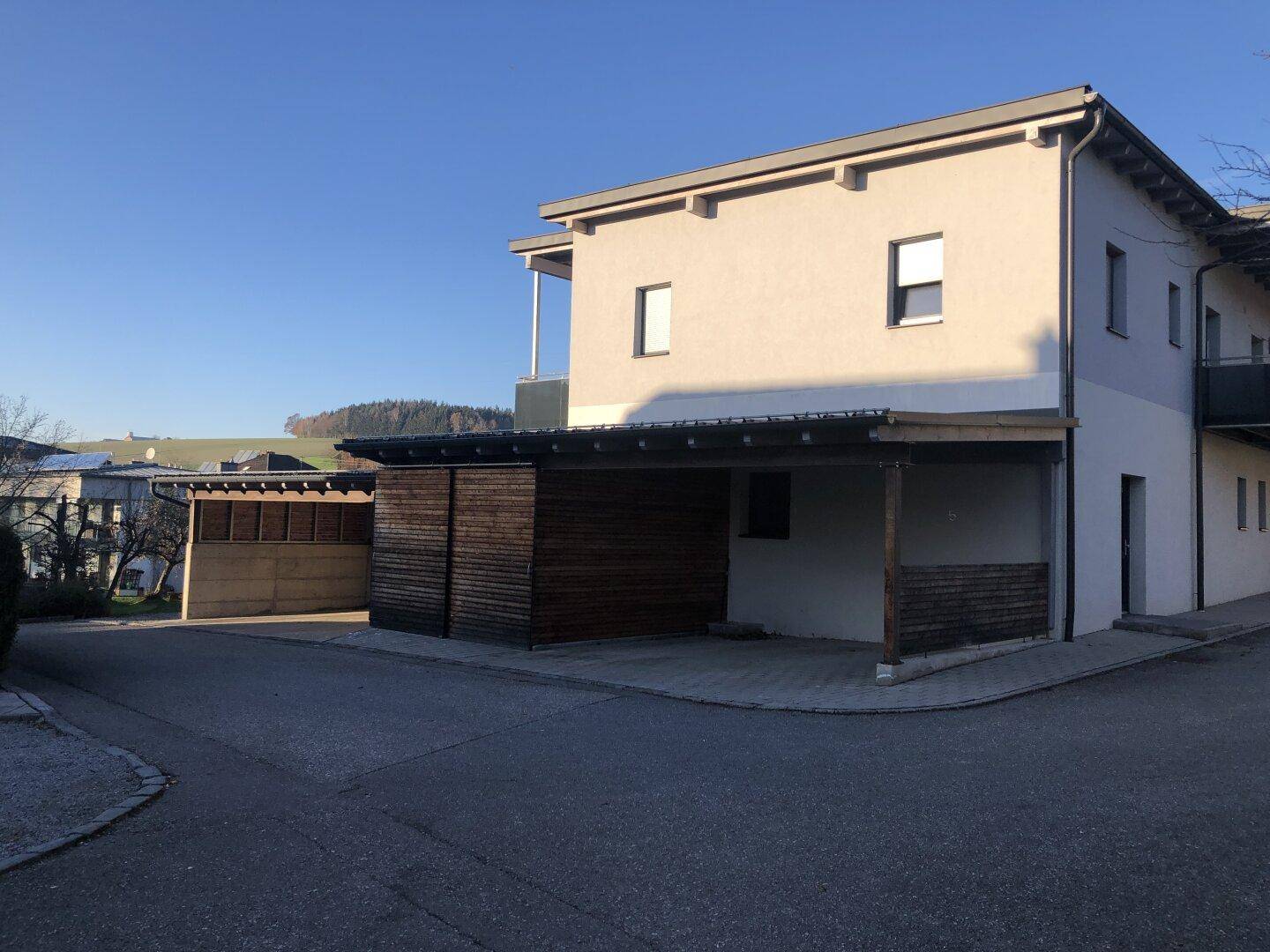 Modernes Wohngebäude mit Carports und Blick auf die umliegende Landschaft.