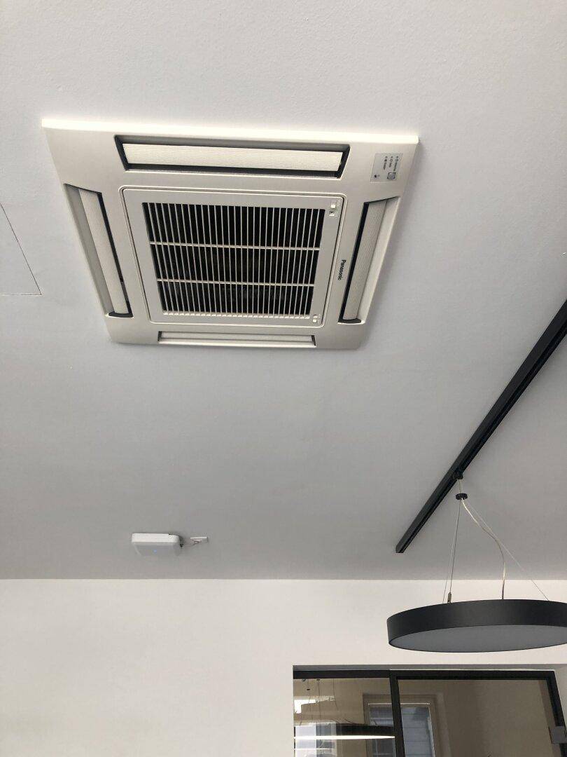 Deckenmontierte Klimaanlage in einem modernen Raum mit weißer Decke und minimalistischer Beleuchtung.