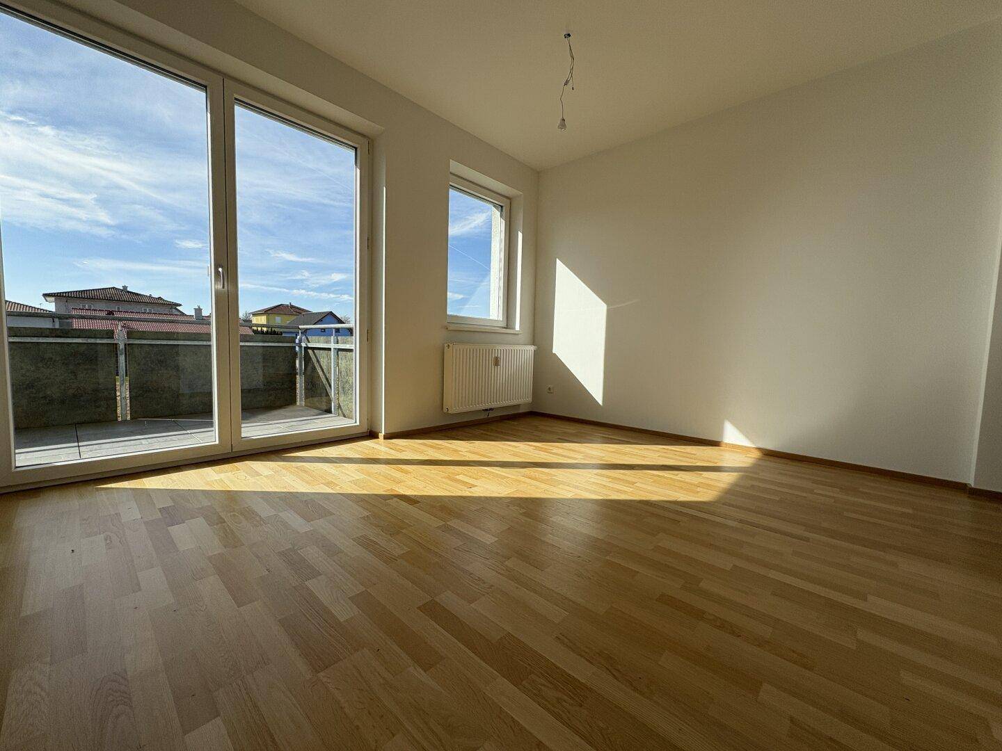 Helles Zimmer mit Parkettboden und direktem Zugang zu einem sonnigen Balkon.