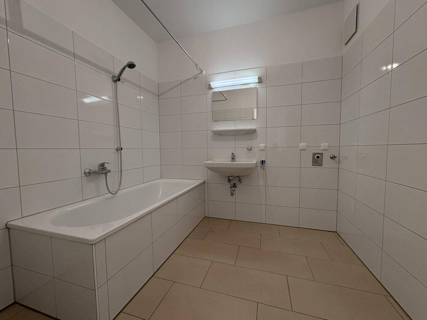 Gefliestes Badezimmer mit Badewanne, Dusche und Waschbecken, in gutem Zustand.