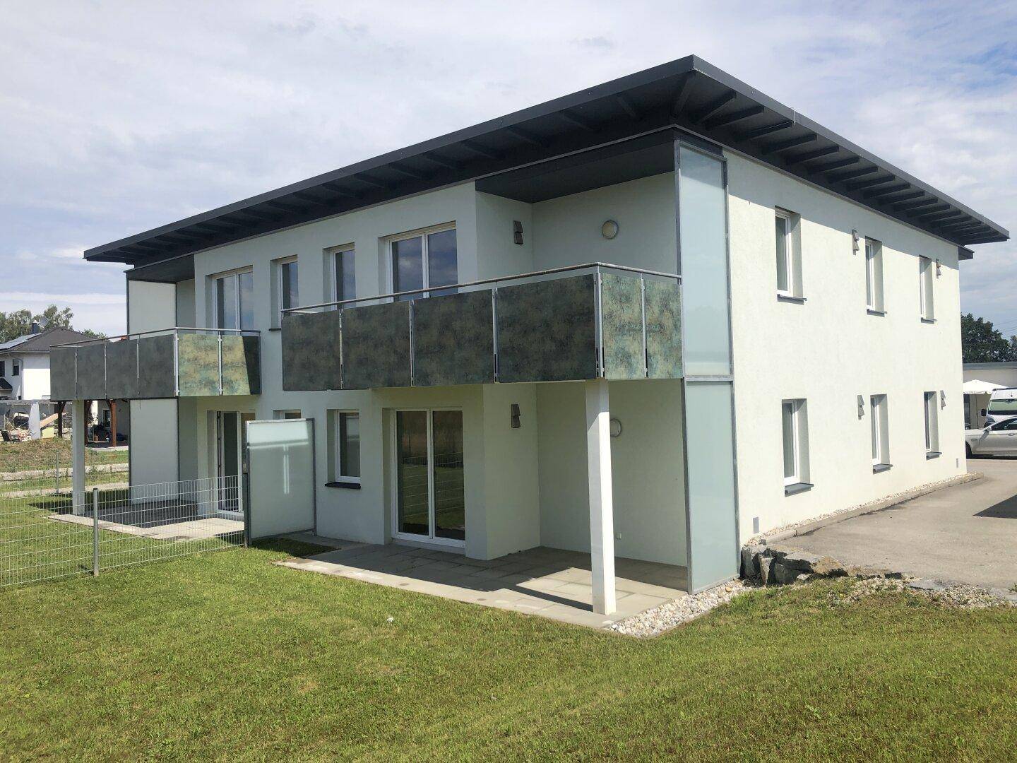 Moderne Wohnanlage mit Balkonen und Terrassen, umgeben von einer gepflegten Rasenfläche.