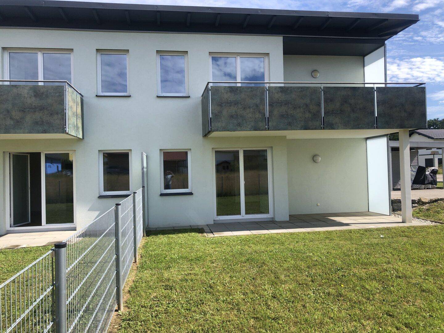 Rückseite des Gebäudes mit Rasenfläche und Terrassenzugang, ideal für Outdoor-Aktivitäten.