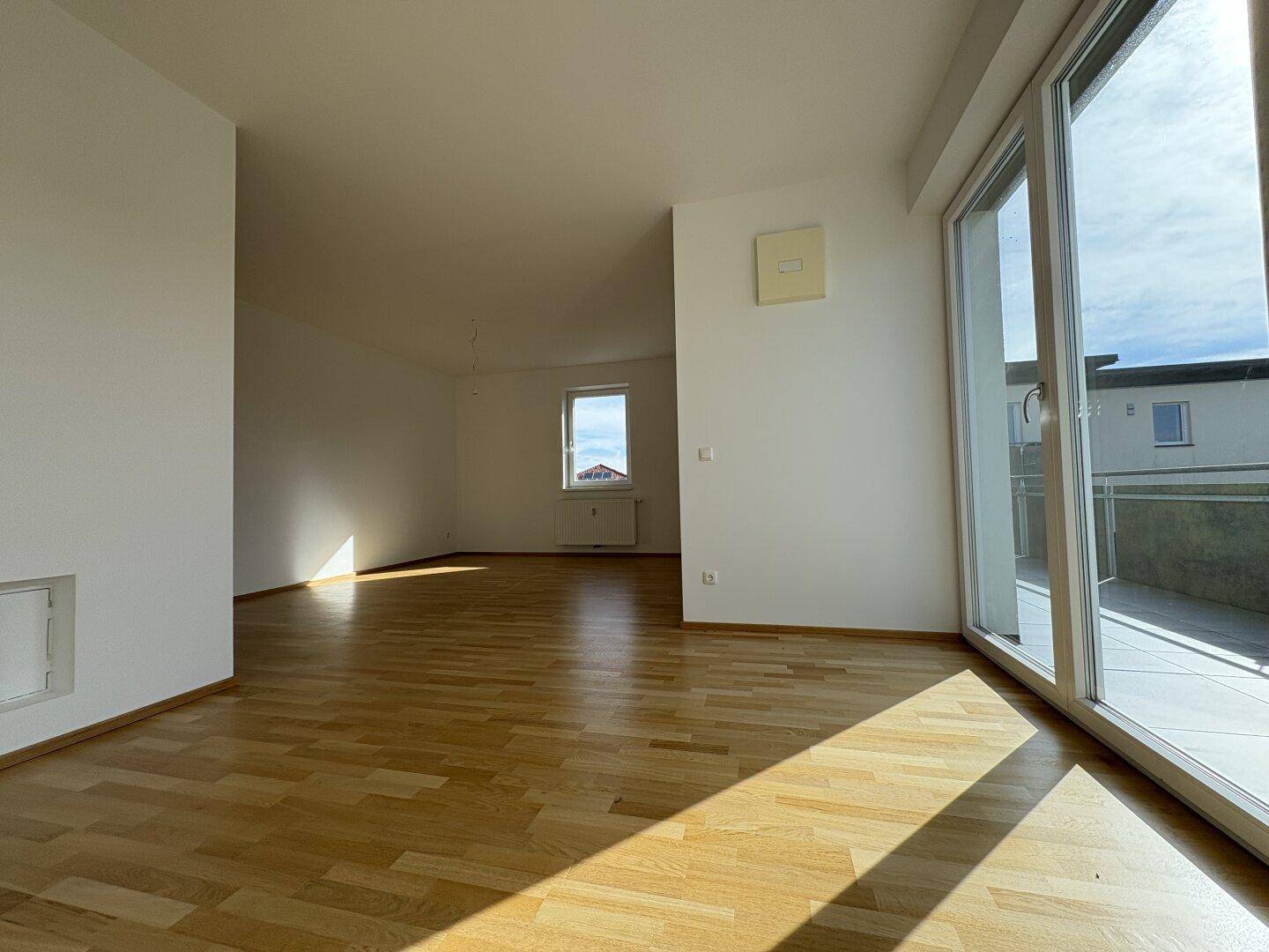 Heller Wohnraum mit großen Schiebetüren, die viel Licht hereinlassen und Zugang zum Außenbereich bieten.