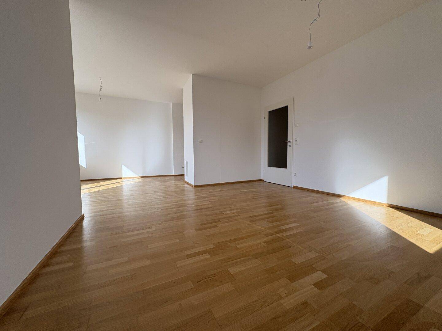 Heller und geräumiger Wohnbereich mit Parkettboden, ideal für eine moderne Einrichtung.