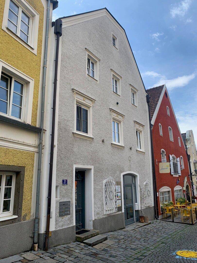 Historische Fassade eines Gebäudes in einer gepflasterten Straße mit angrenzenden Häusern.