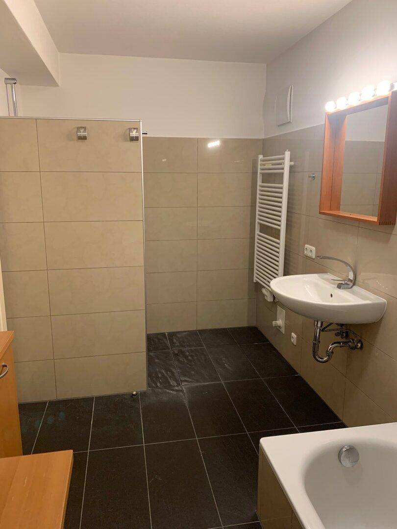Geräumiges Badezimmer mit Badewanne, Dusche, Waschbecken und beheiztem Handtuchhalter.