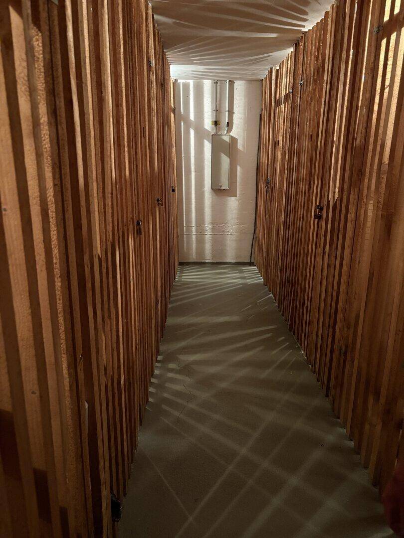 Kellerabteil mit Holzwänden und Betonboden, ideal für zusätzlichen Stauraum.