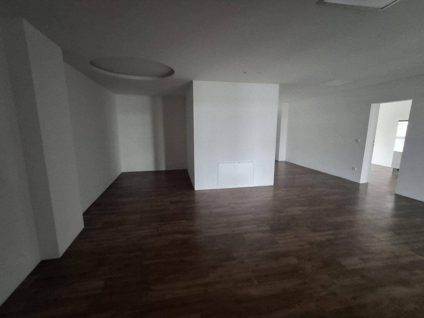 Großer, leerer Raum mit Laminatboden und einer dekorativen runden Deckenvertiefung, bereit zur Nutzung.
