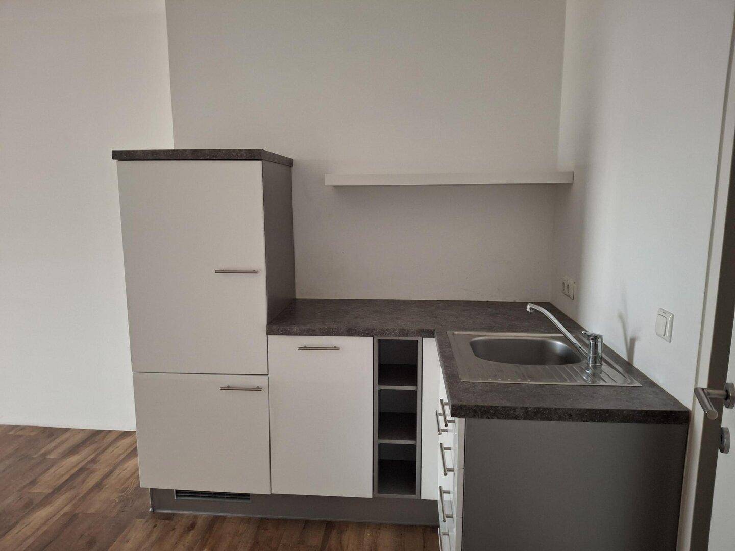 Detailansicht einer kompakten Küchenzeile mit Spüle, Unterschränken und einer kleinen Ablagefläche.