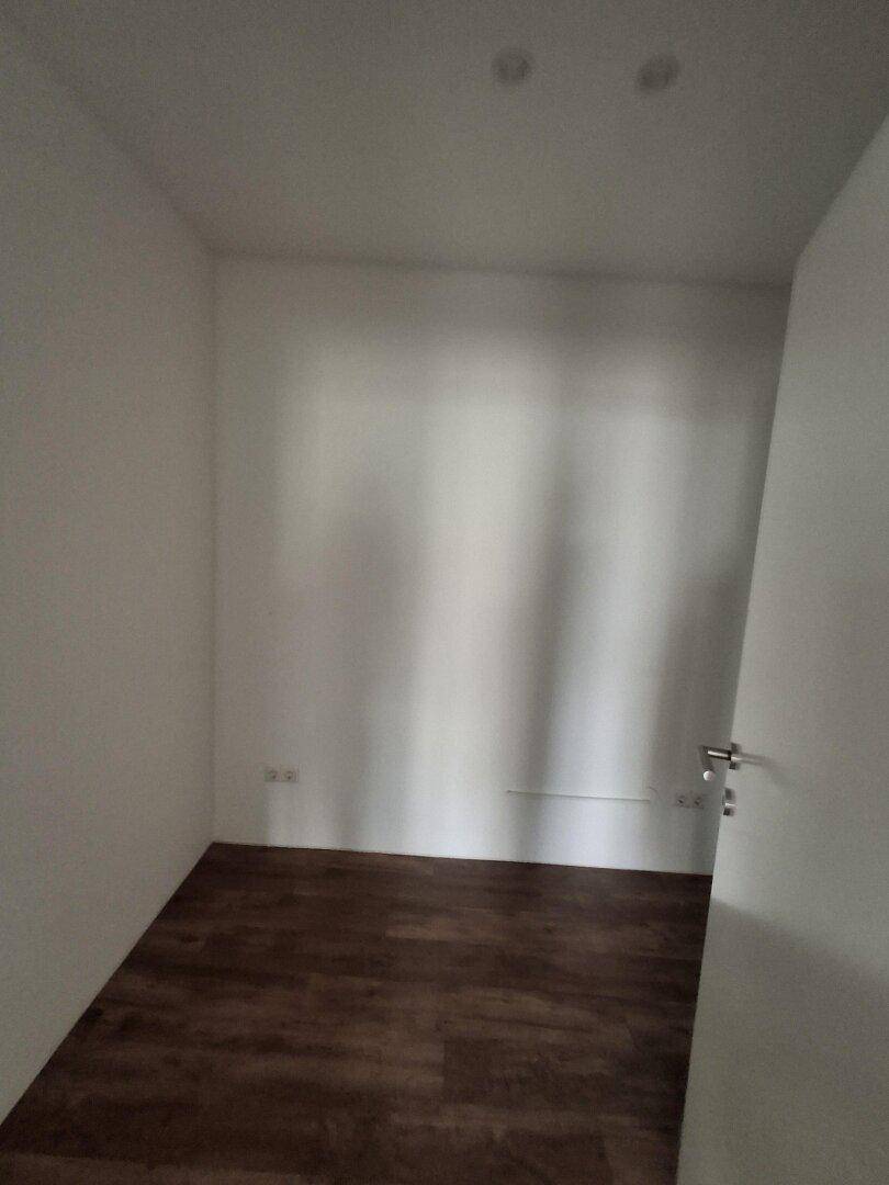 Kleiner, heller Raum mit Laminatboden und weißen Wänden, geeignet als Büro oder Abstellraum.