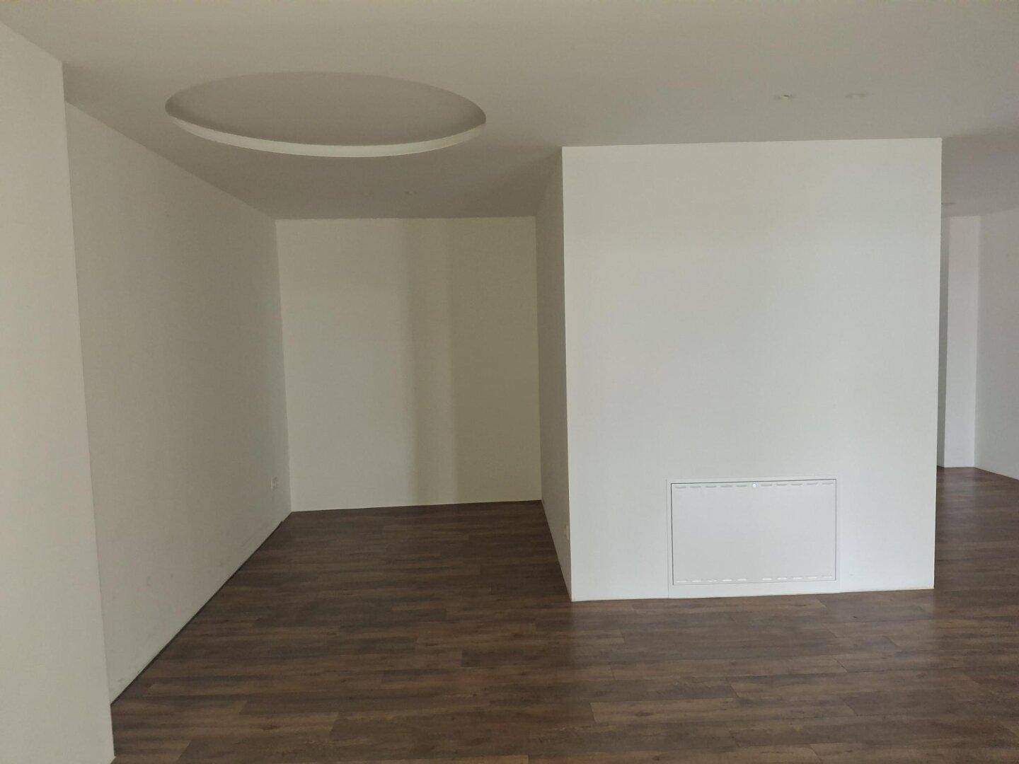 Geräumiger, heller Raum mit Laminatboden und einer stilvollen runden Deckenvertiefung, neuwertig.