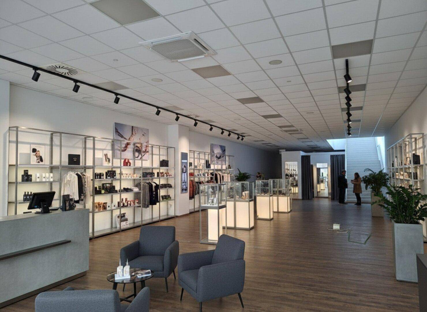 Geräumiger Einzelhandelsbereich mit modernen Regalen, beleuchteten Auslagen und einem stilvollen Empfangstresen.