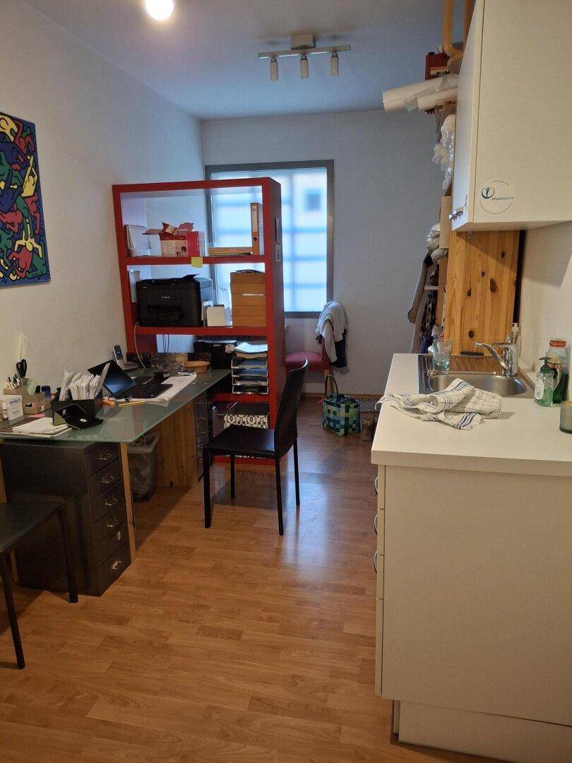 Kombinierter Büro- und Küchenbereich mit Schreibtisch, Regalen und kleiner Spüle für effizientes Arbeiten.