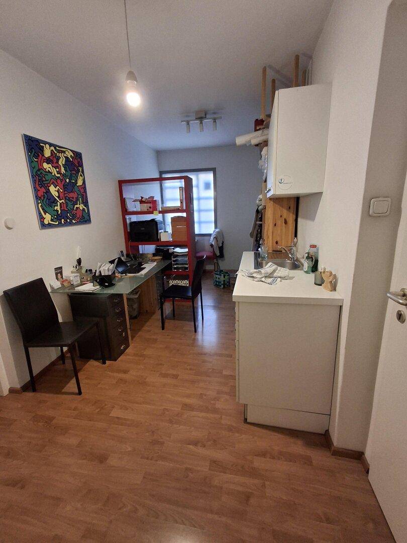 Funktionaler Raum mit Arbeitsbereich, Küchenzeile und Stauraum, ideal für kleine Büros oder Studios.