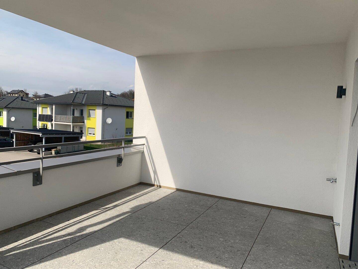 Heller Balkon mit modernem Fliesenboden und schlichtem Design, ideal für entspannte Stunden im Freien.