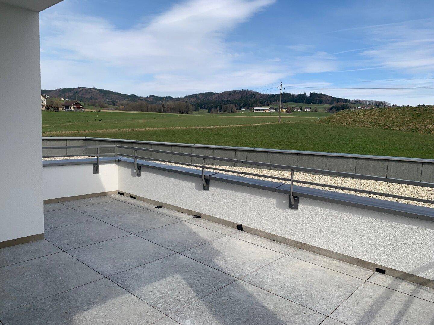 Geräumige Außenterrasse mit Fliesenboden und Metallgeländer, bietet einen weiten Blick auf die Landschaft.