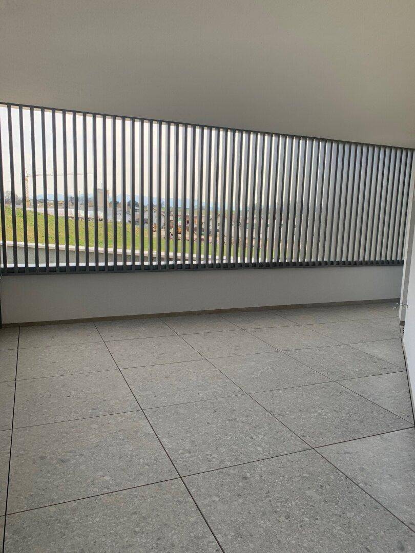 Geräumiger Balkon mit Fliesenboden und vertikalen Lamellen als Brüstung, der einen weiten Blick ermöglicht.