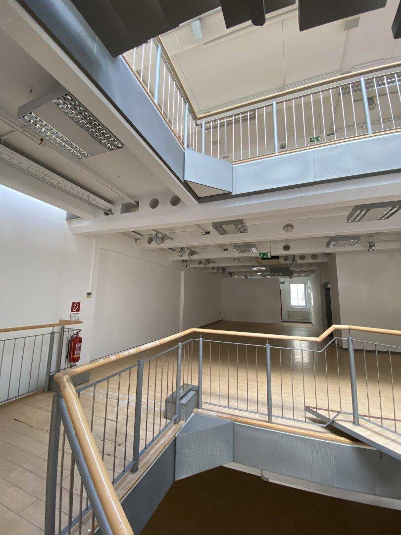 Blick von einer oberen Ebene auf den weitläufigen Ladenbereich mit Holzboden und moderner Treppe.