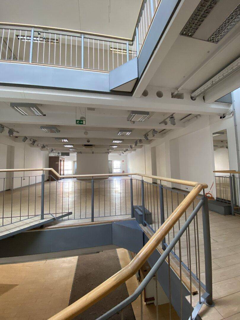 Blick von einer oberen Ebene auf den weitläufigen Ladenbereich mit Holzboden und moderner Treppe.