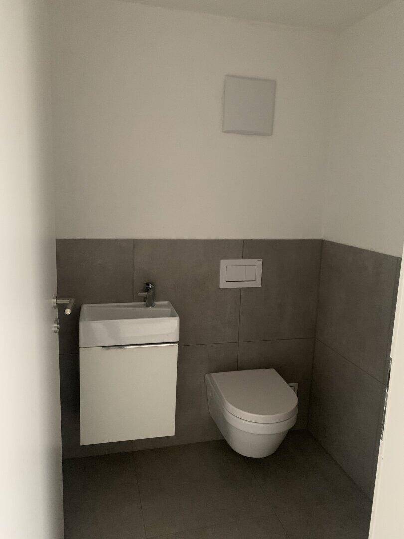 Kleines Gäste-WC mit wandhängendem WC und kompaktem Handwaschbecken.