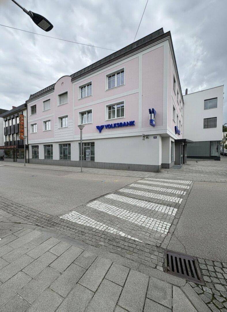 Gesamtansicht des Gebäudes mit der Volksbank-Filiale an einer städtischen Kreuzung mit Zebrastreifen.