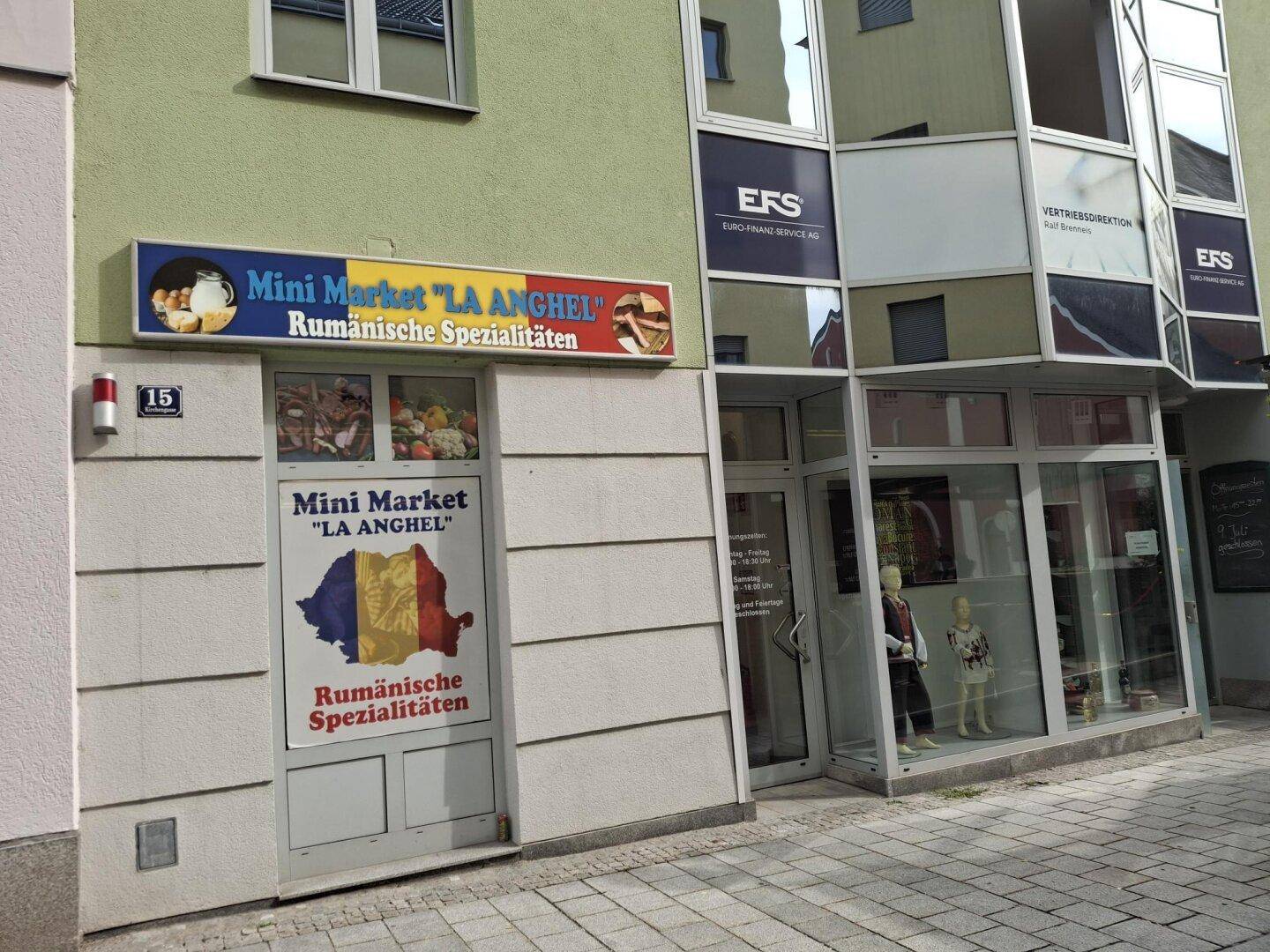 Außenansicht eines Gebäudes mit einem Mini-Markt im Erdgeschoss und einem angrenzenden Büro mit Glasfassade.