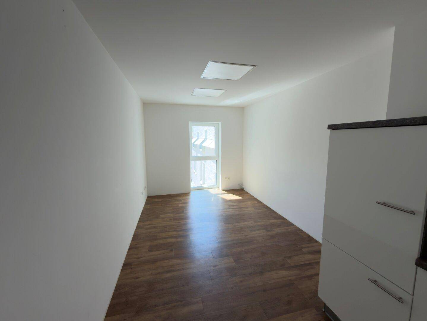 Kleiner, heller Raum mit Holzboden und einer Tür, die ins Freie führt, geeignet als Einzelbüro oder Abstellraum.