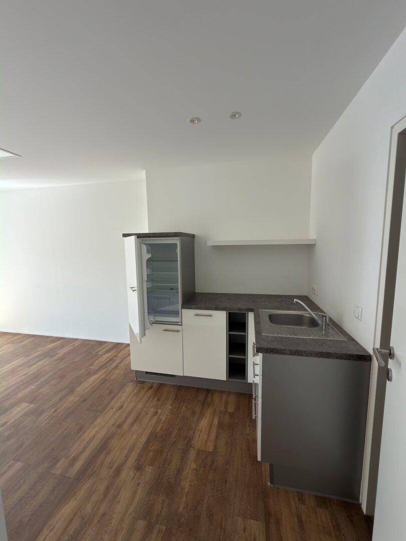 Funktionale Küchenzeile mit Spüle, Arbeitsplatte und kleinem Kühlschrank, ideal für eine kompakte Raumnutzung.