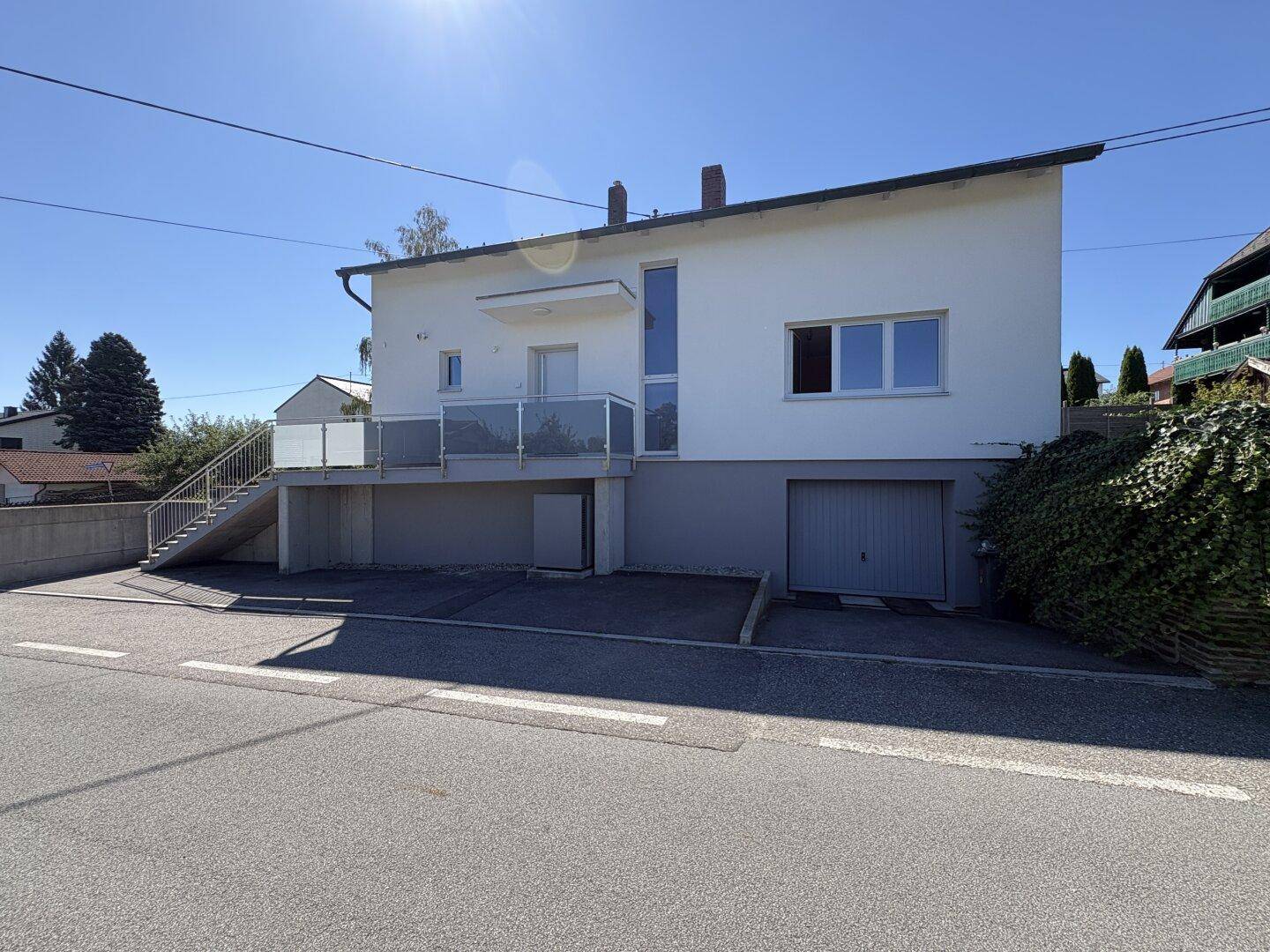 Modernes Einfamilienhaus mit Balkon und Garage, von der Straße aus gesehen.