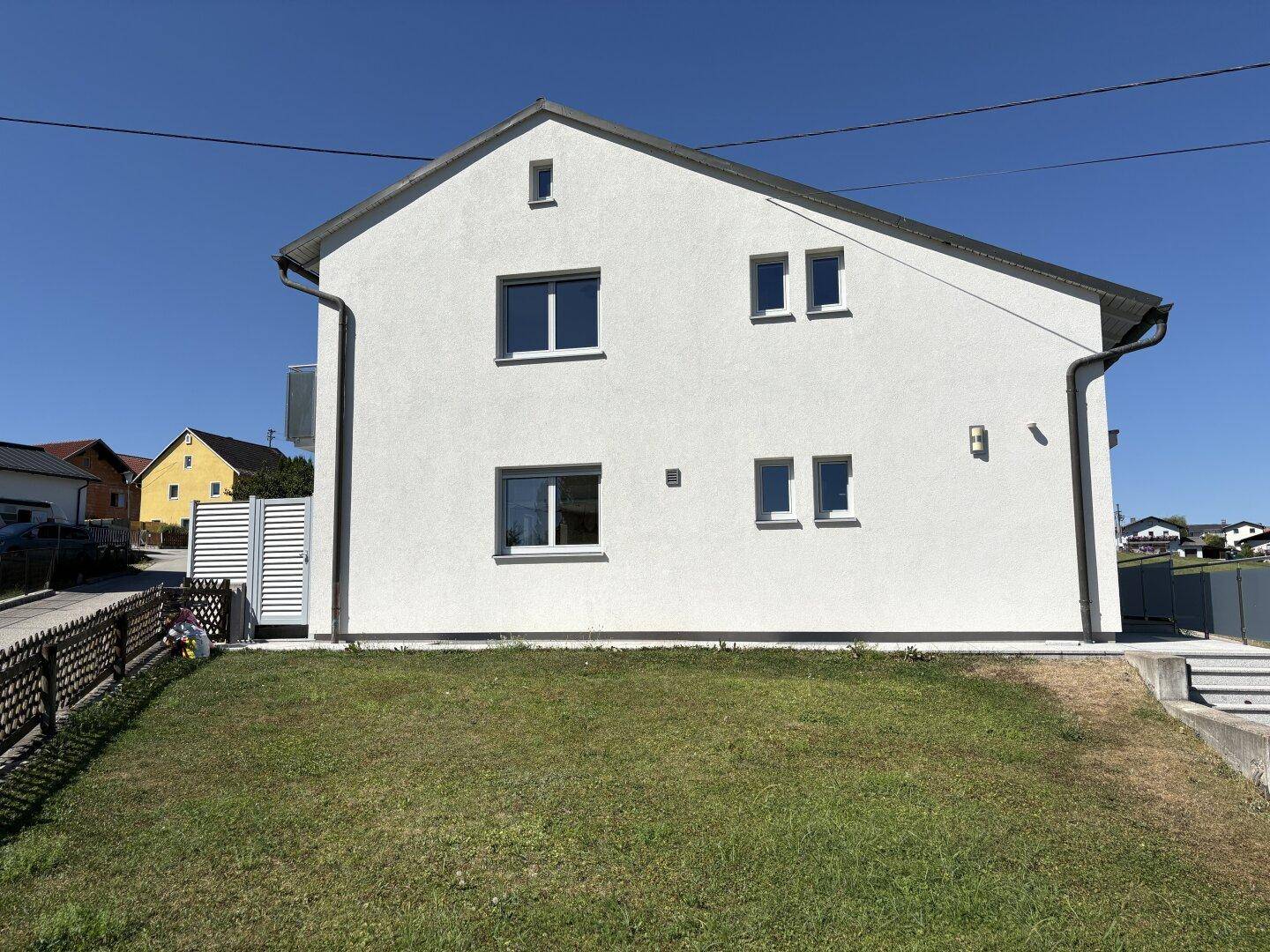 Seitenansicht des Hauses mit gepflegtem Rasen und schlichter Fassade.