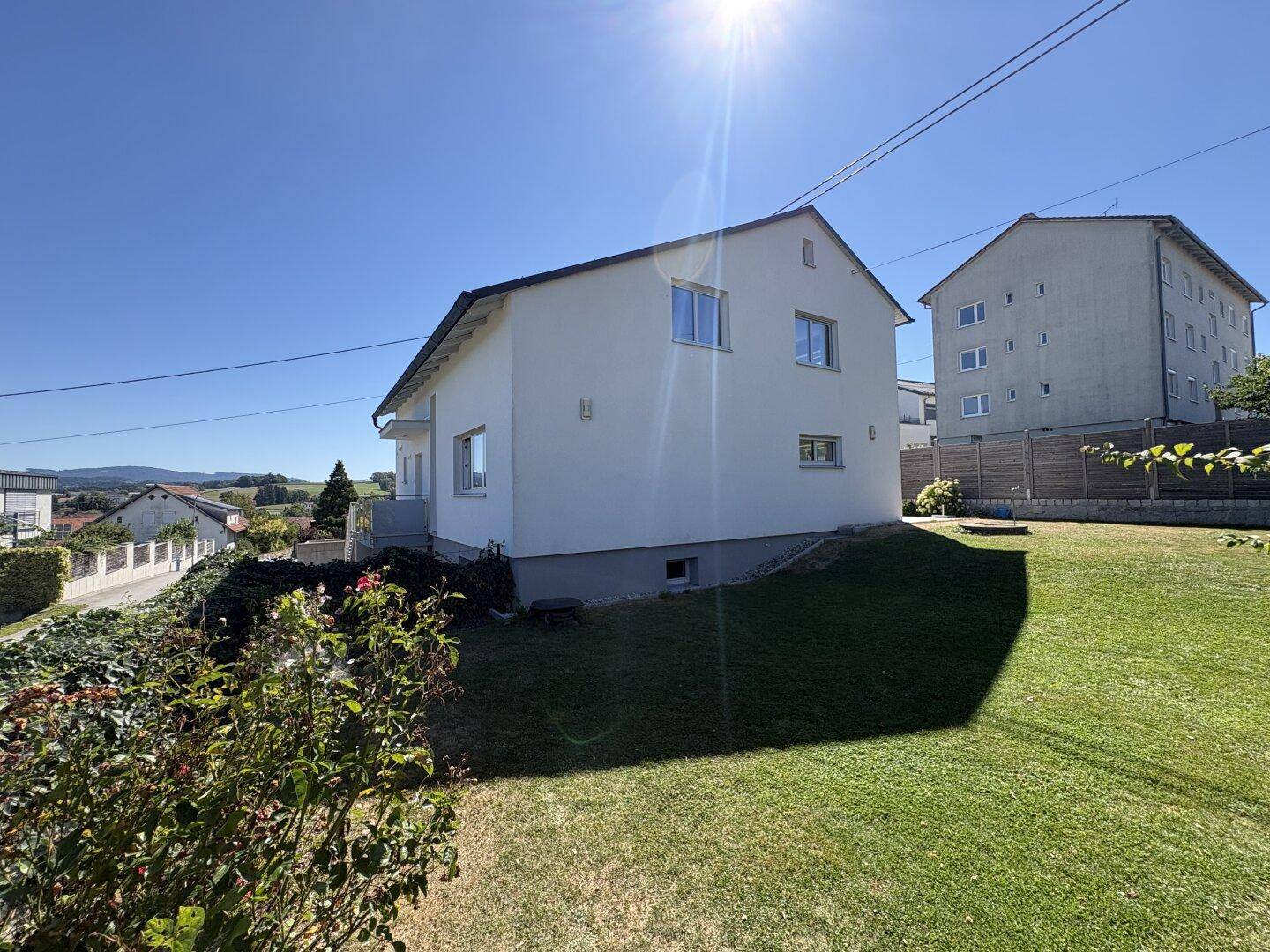 Haus in ländlicher Umgebung mit weitem Rasen und sonnigem Ausblick.