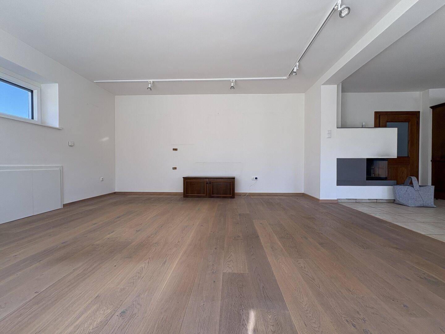 Heller Wohnbereich mit Holzboden und einem modernen Kamin als stilvolles Element im Raum.