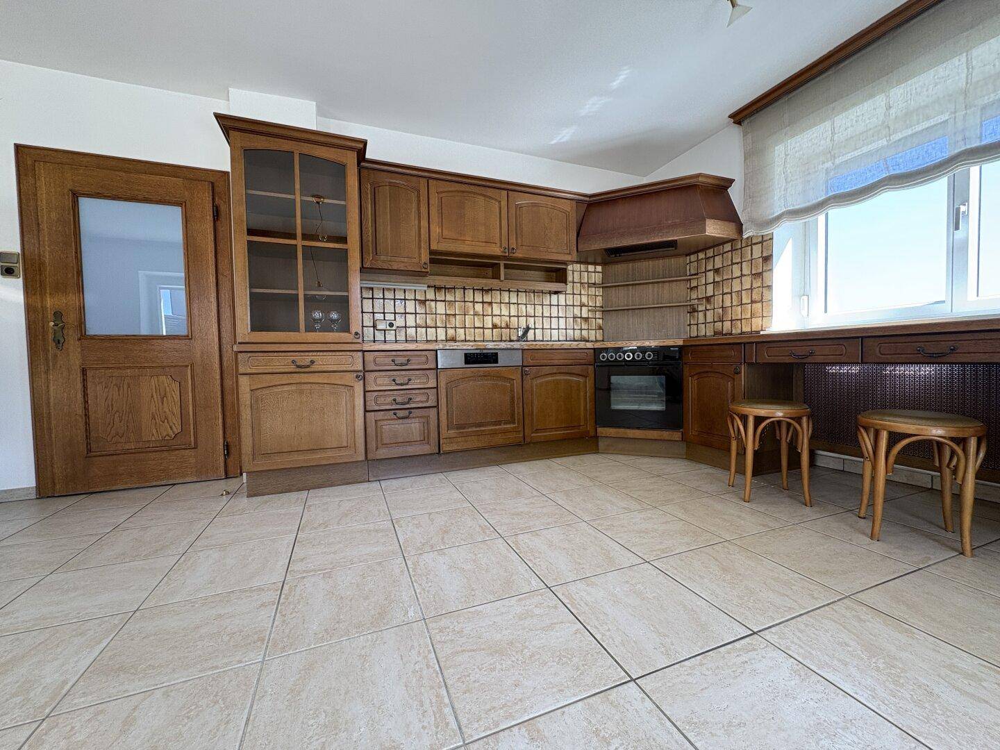 Rustikale Holzküche mit integrierten Geräten, Fliesenboden und traditionellen Details an den Schränken.