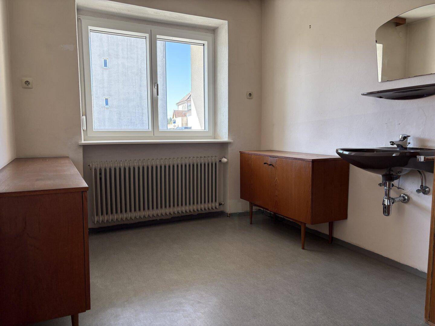 Einfacher Raum mit Linoleumboden, Fenster und einem kleinen Waschbecken, ideal als Hauswirtschaftsraum.
