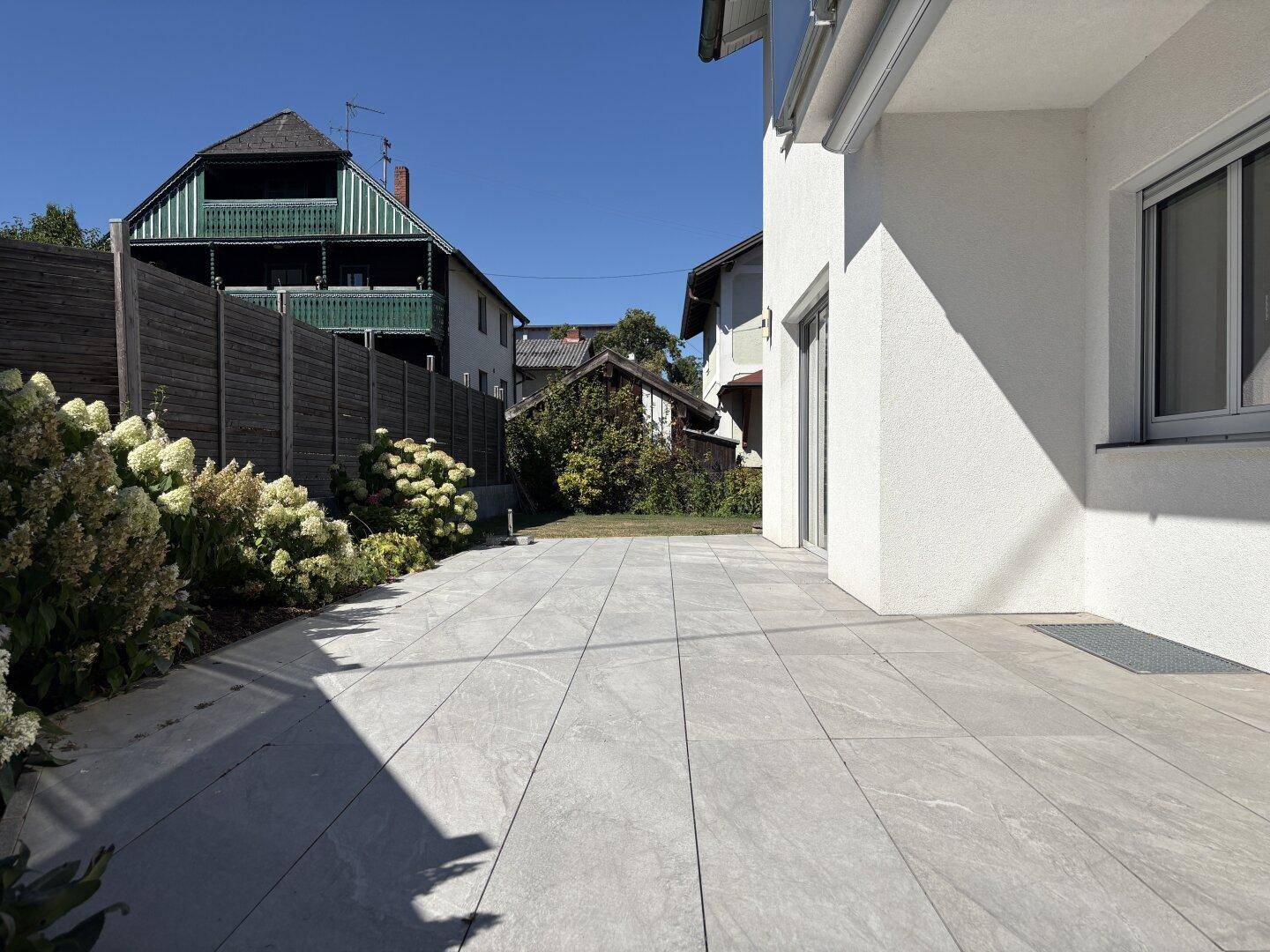 Weitläufige gepflasterte Terrasse neben dem Haus mit Blick auf die Umgebung.