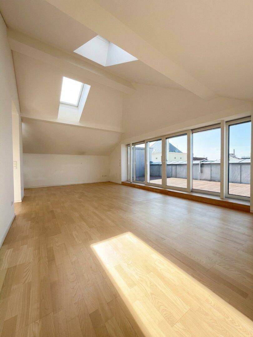 Lichtdurchfluteter Wohnraum mit hellem Holzboden, Dachfenstern und weitem Ausblick.