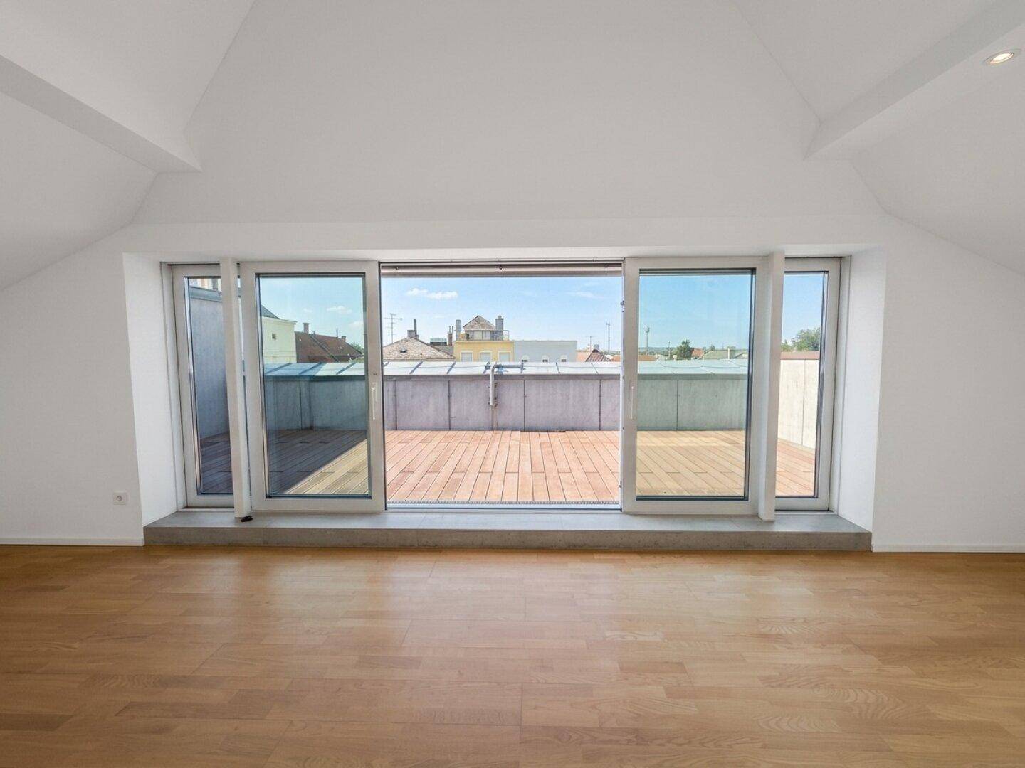 Große Schiebetüren öffnen den Wohnbereich zur weitläufigen Dachterrasse mit Stadtblick.