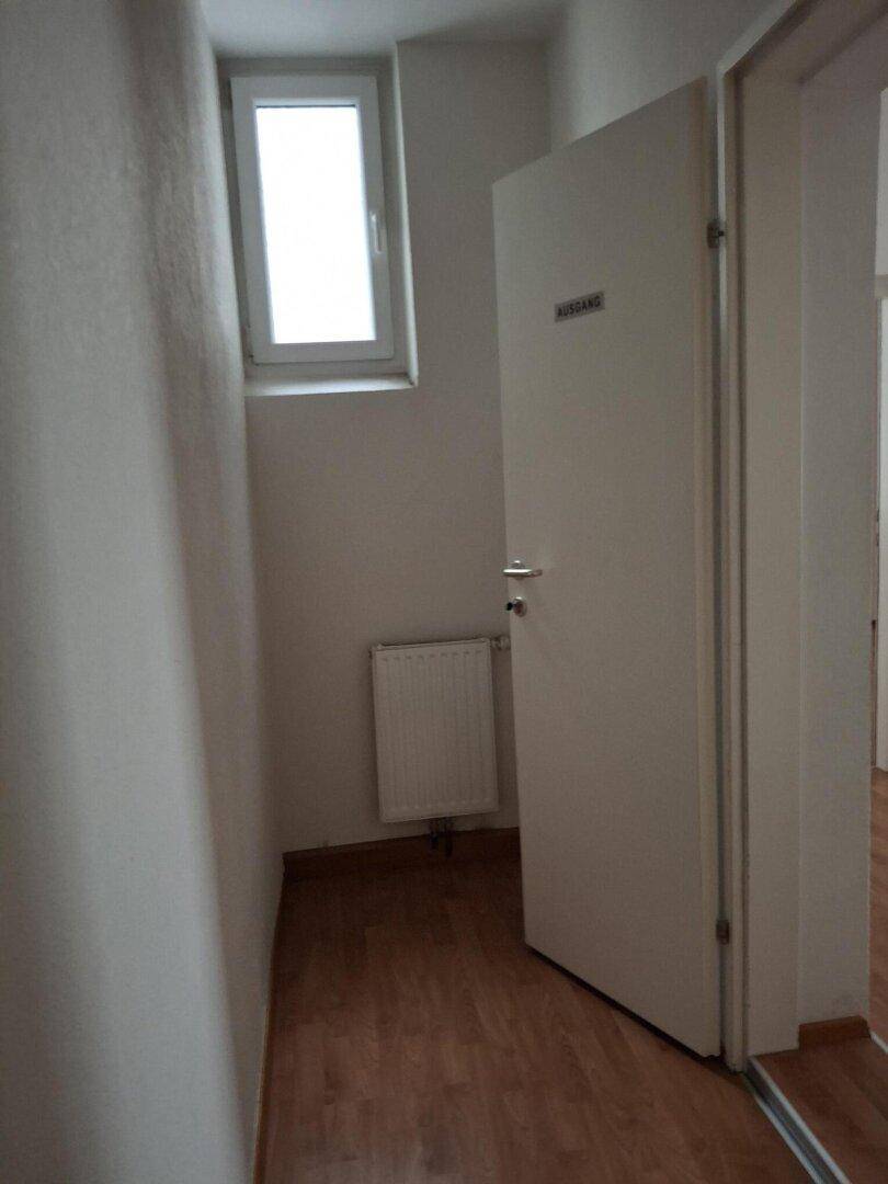 Kleiner Eckbereich mit Laminatboden, einem Fenster und einem Heizkörper unter dem Fenster.
