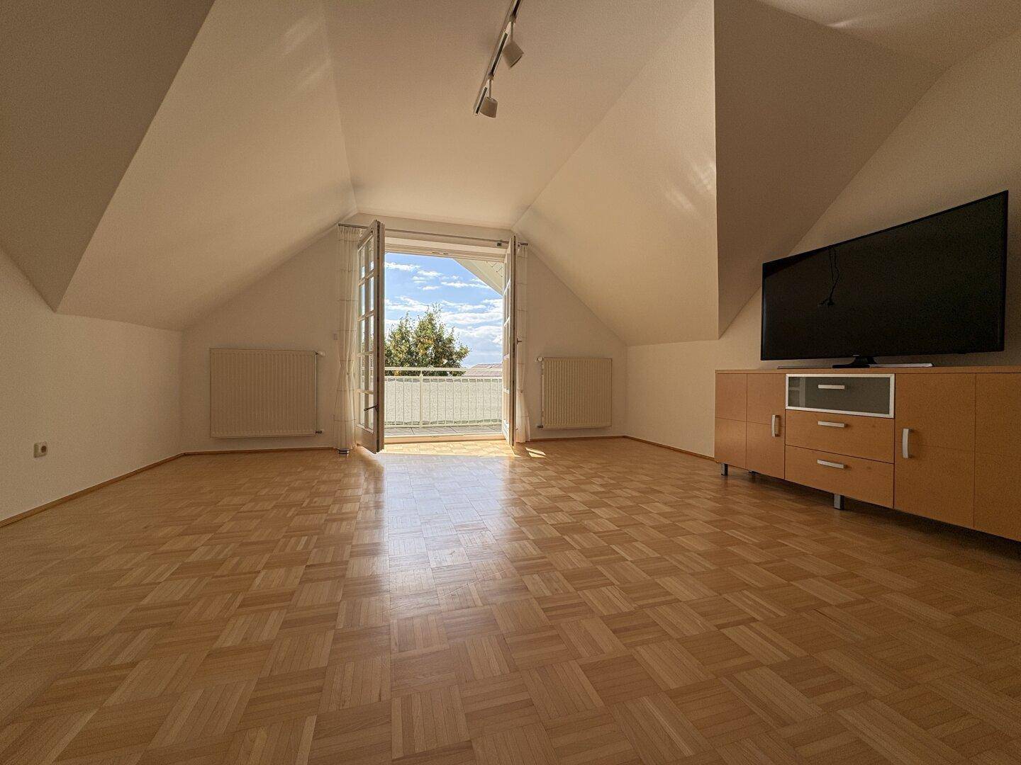 Helles Wohnzimmer mit Balkonzugang, Parkettboden und weitem Blick in die Ferne.