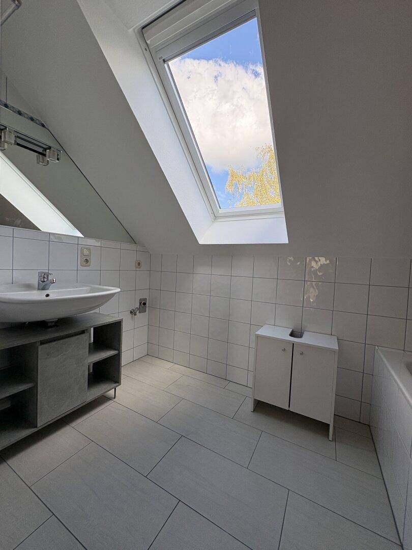 Modernes Badezimmer mit Waschtisch, Fliesenboden und Dachfenster.