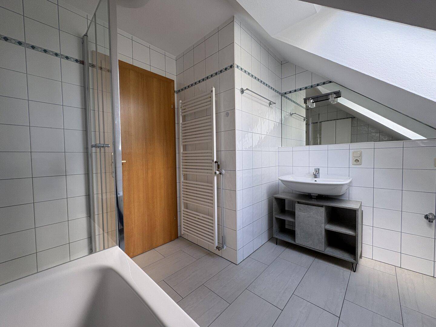 Badezimmer mit Waschtisch, Spiegel und beheiztem Handtuchhalter.