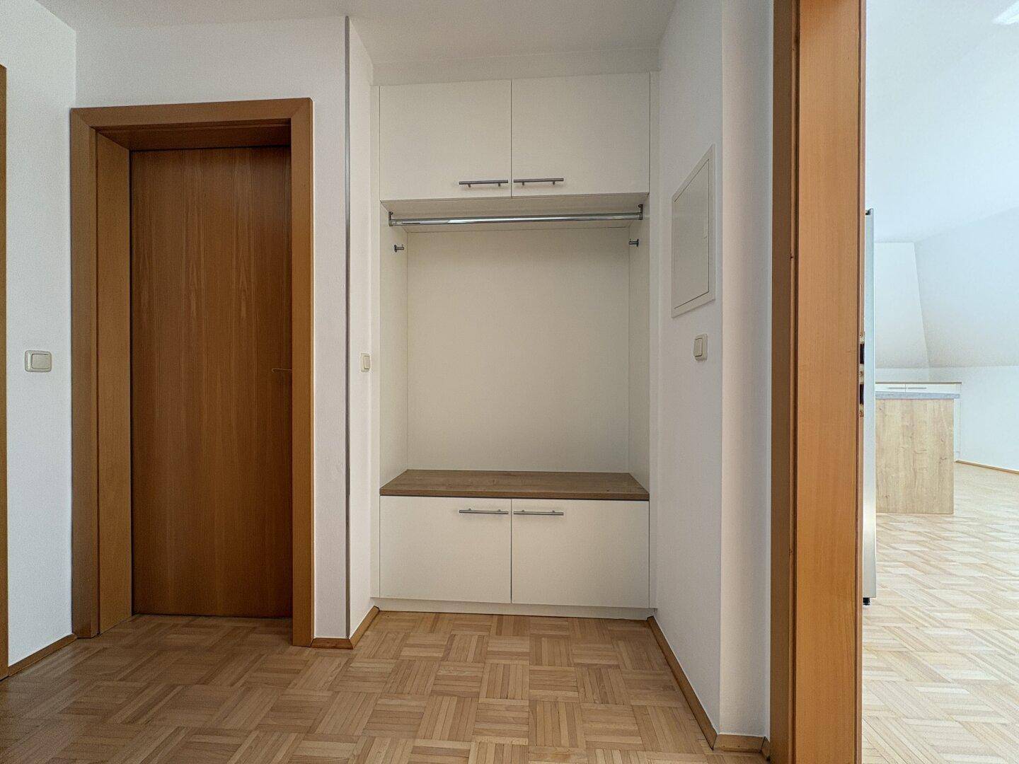 Eingangsbereich mit Garderobenschrank, Parkettboden und Holztüren.